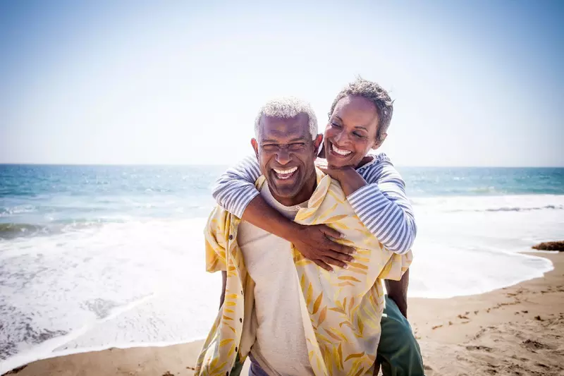 An older couple smiling while at the beach.