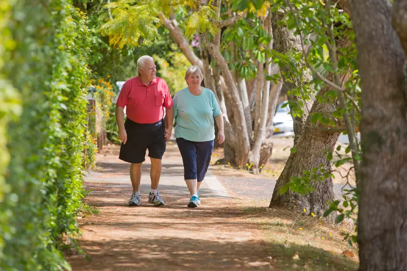 Older couple walking down a shaded street