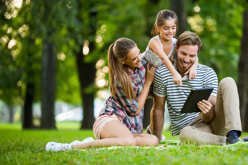 Happy family in park reading a tablet 
