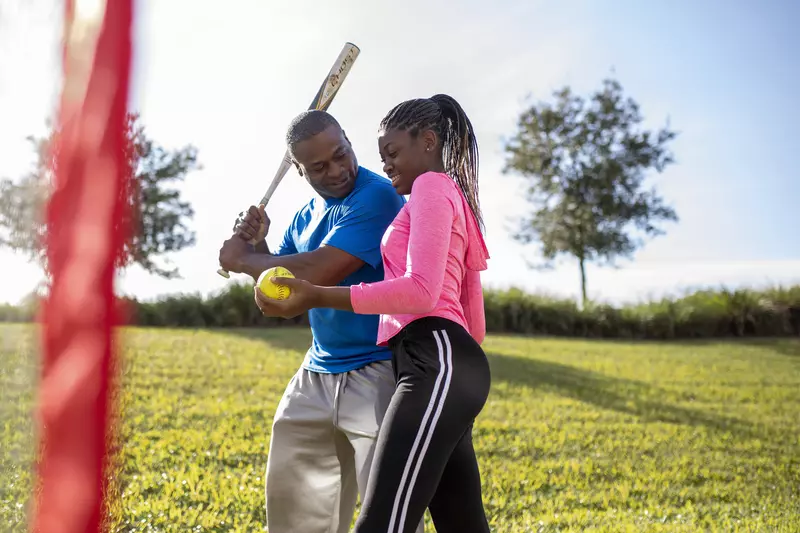 A father and daughter playing softball outdoors