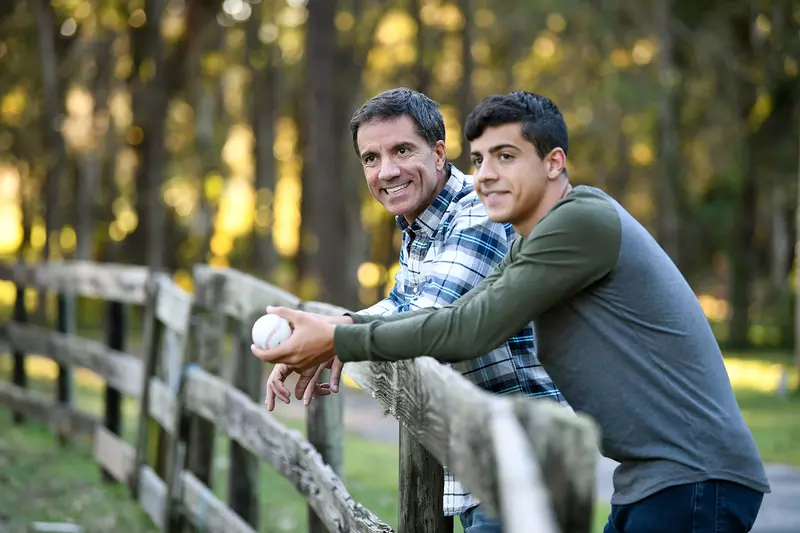 A father and son leaning forward on a fence