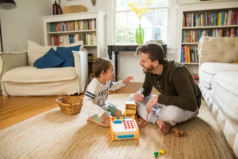 A dad playing a board game with his son in the family room.
