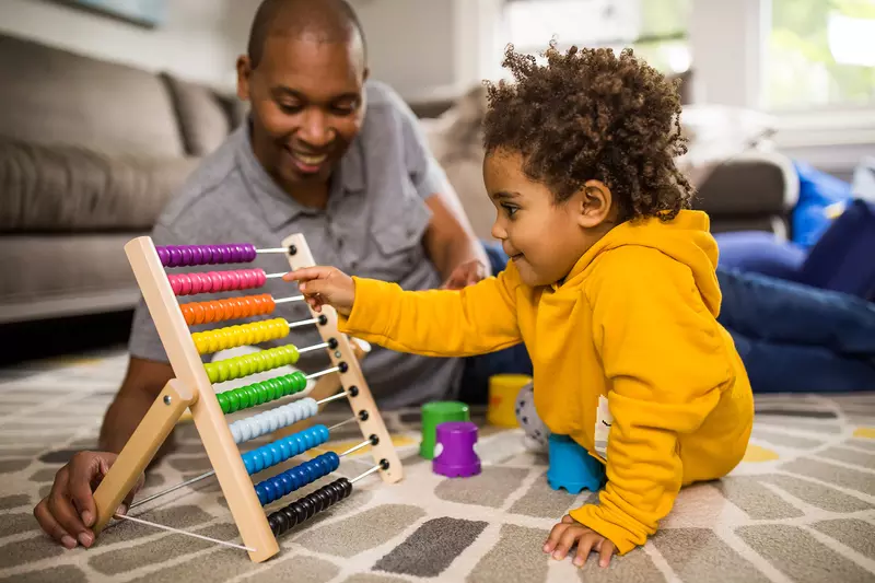 A dad playing abacus with baby son in the family room.