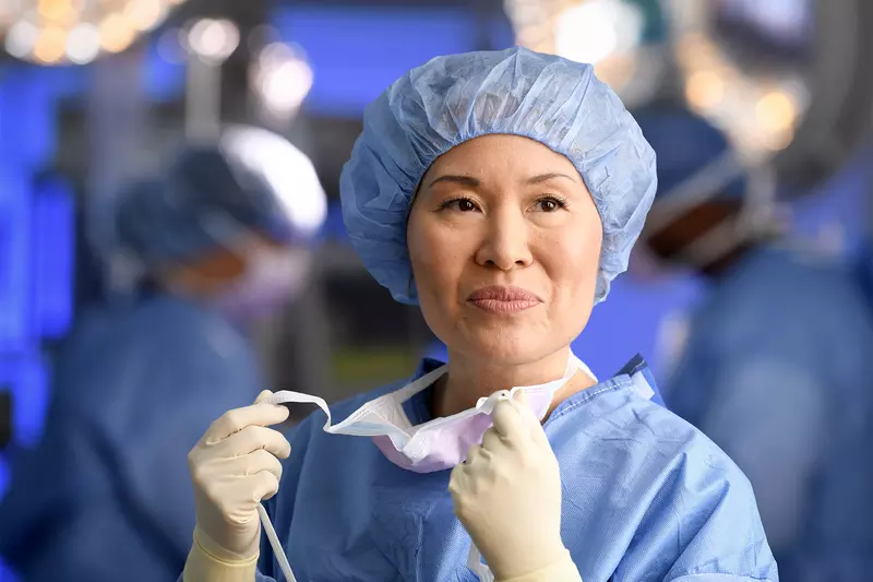 Smiling female surgeon taking off her mask