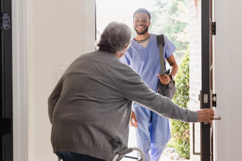 A Patient Opens Their Front Door to Allow a Therapist in Their Home