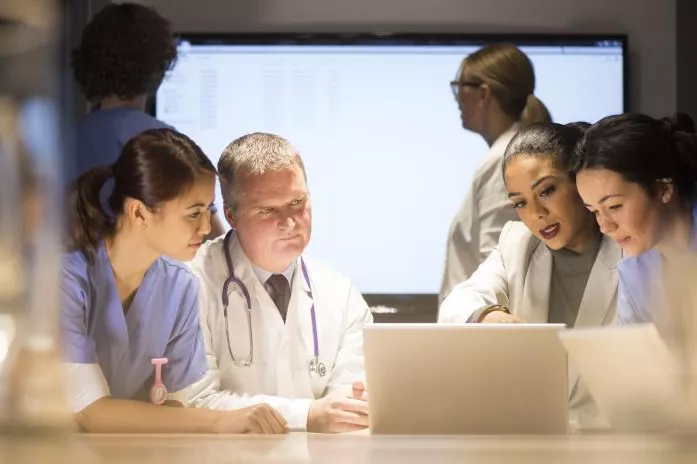 Doctors Huddle Around a Laptop Going Over Research