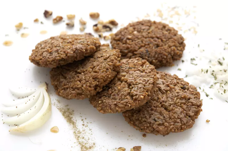 Five millet patties on white surface with onion garnish