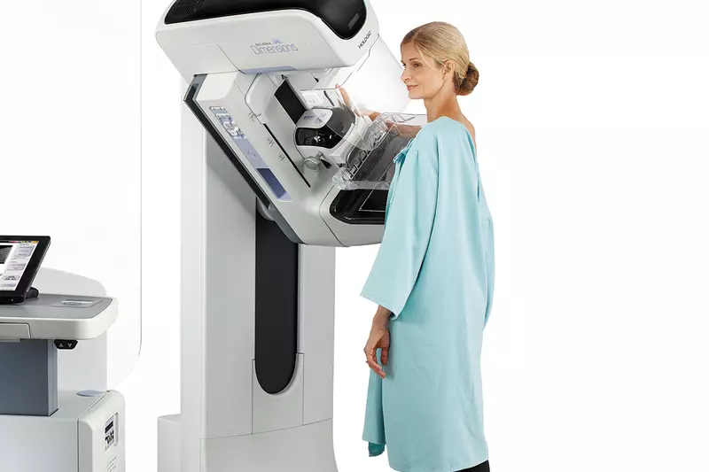 A woman getting a mammogram done with a 3D mammography machine