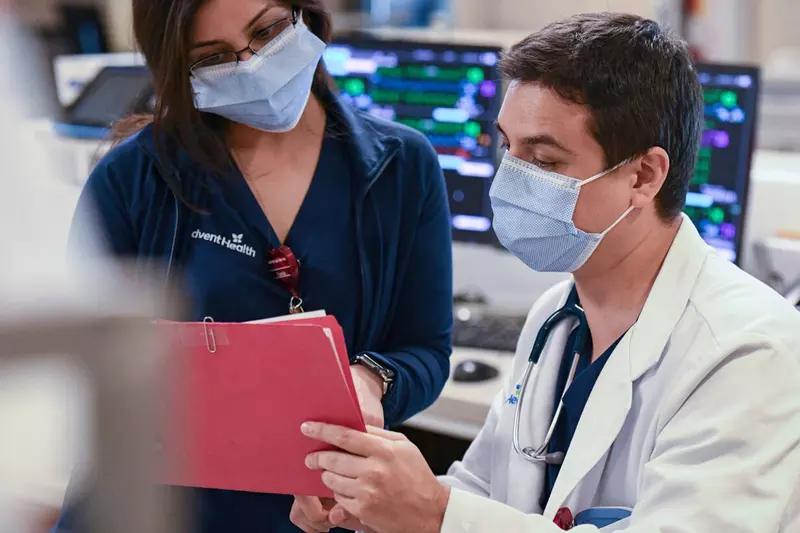 An Adventhealth physician and nurse going through a patient's file.