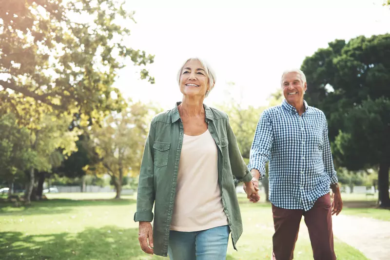 Elderly couple holding hands and walking in a park