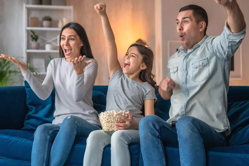 A family cheering on their favorite team at home.