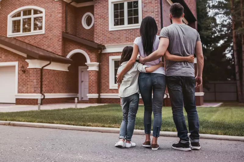 A family looks at their home from the curb.