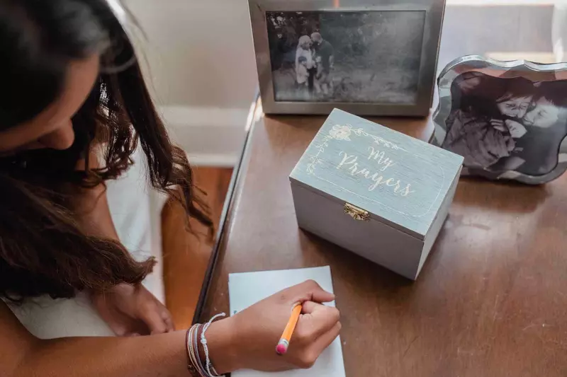 Girl writing prayer with prayer box