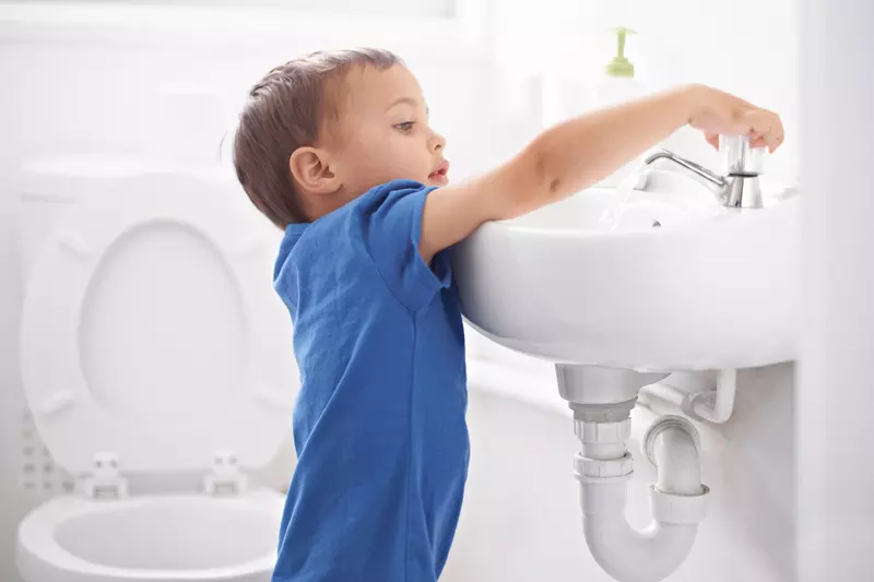 A child turning on the bathroom sink.