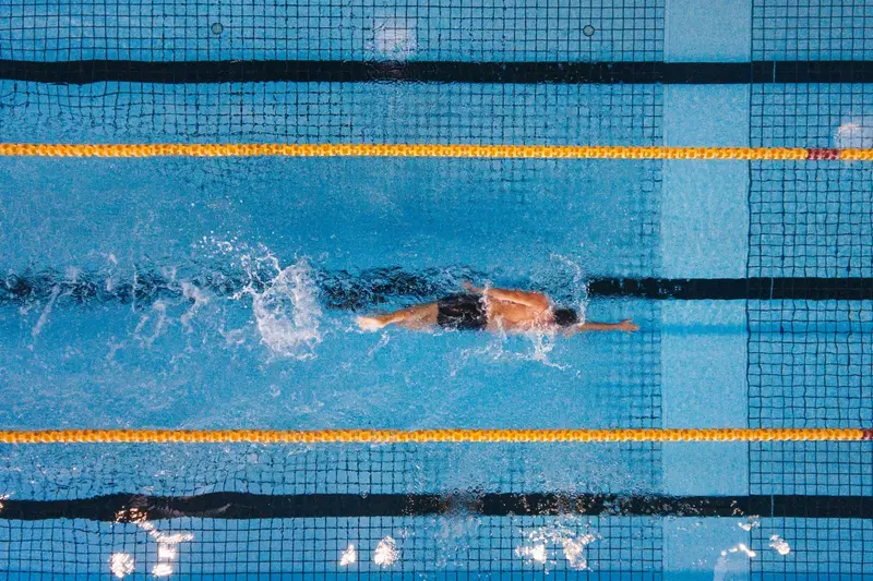 An olympic swimmer paddles freestyle through the water