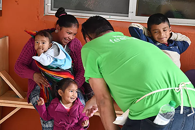 An AdventHealth team member greets a Guatemala family outside a malnutrition center in San Juan, Guatemala.