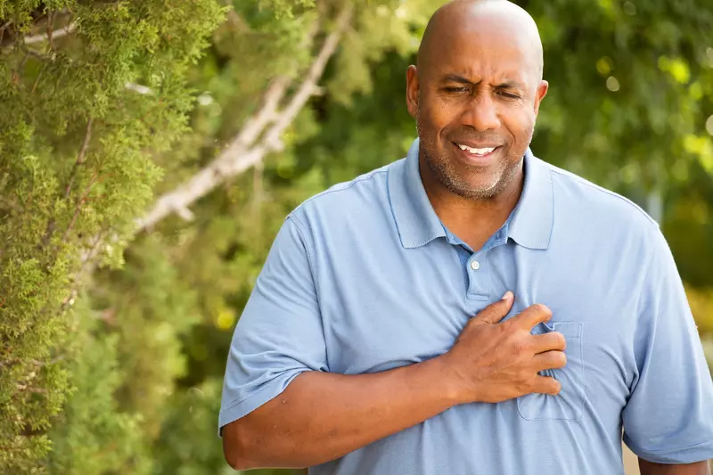 A man experiencing chest pain during a walk outdoors.