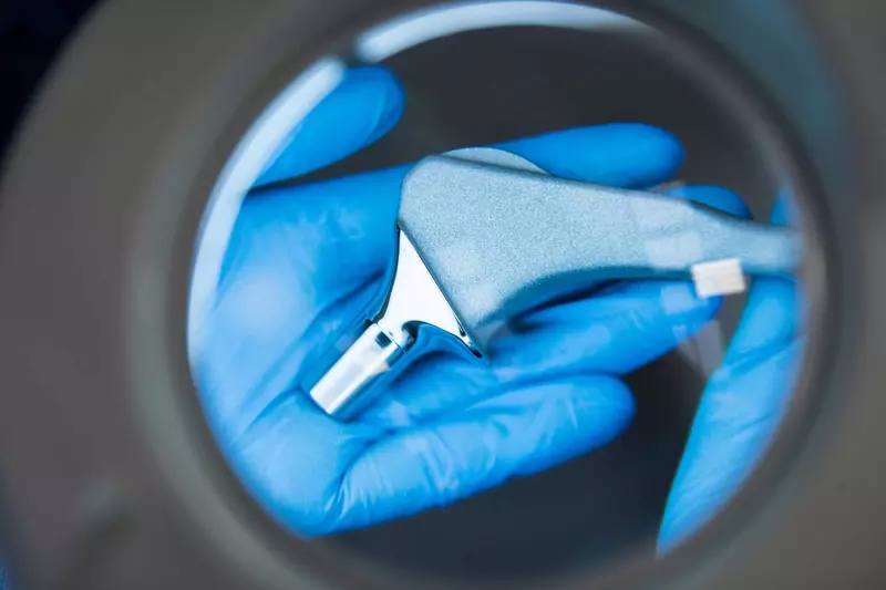 A surgeon holding an ortho tool under a magnifying glass