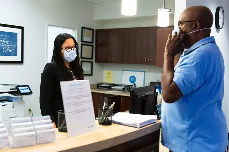 A patient checking in for an appointment and wearing a mask.