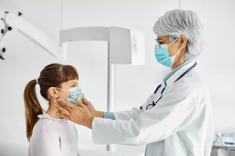 A doctor checking the neck of her pediatric patient with her fingers