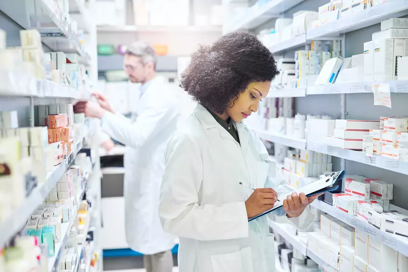 Female and male pharmacist working in an aisle in a pharmacy.