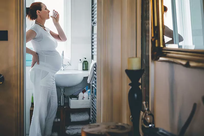A pregnant woman drinking water.