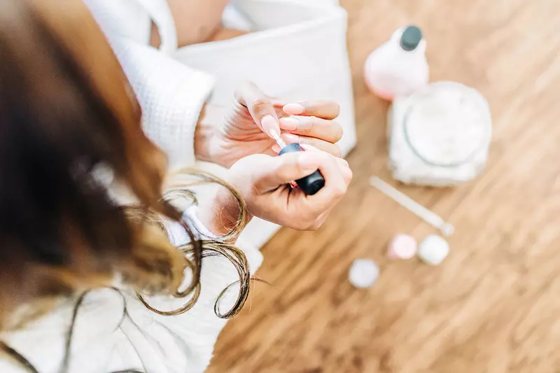 A woman takes some time for self care by painting her nails.