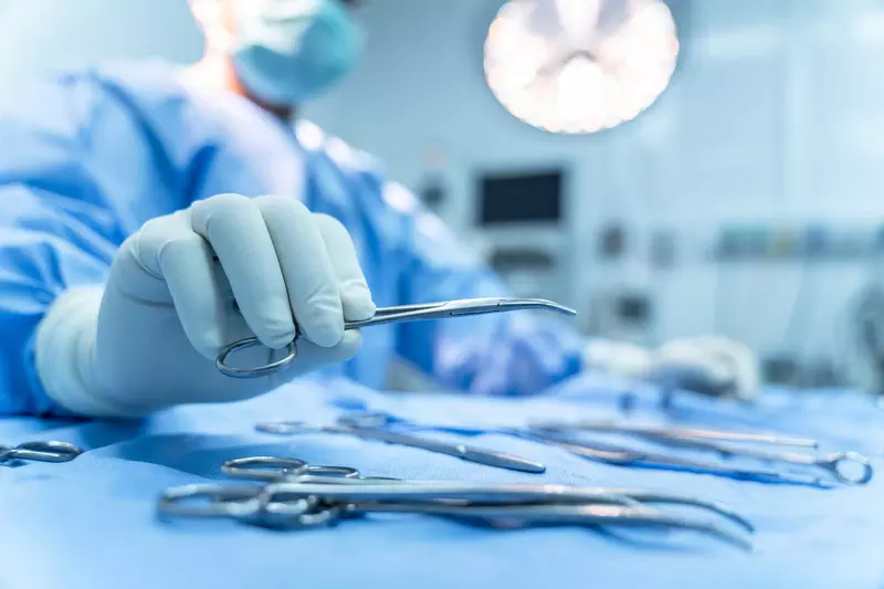 A surgeon picking up a pair of surgical scissors