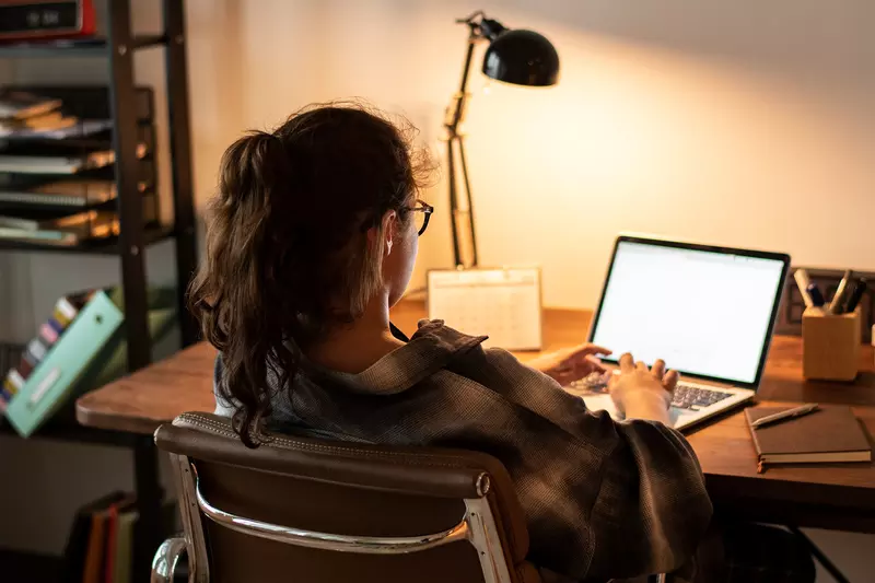 A teenager does her homework on her laptop at home