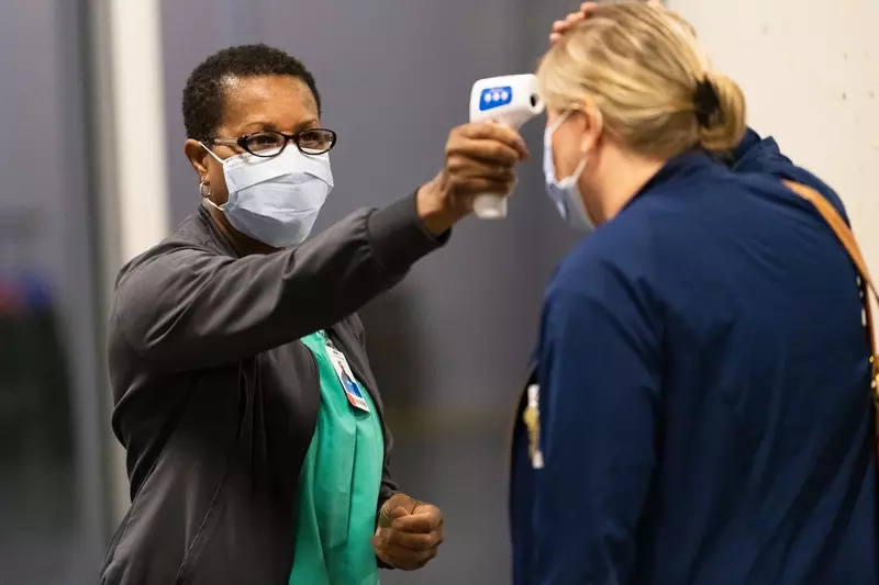 A woman has her temperature checked before a visit.