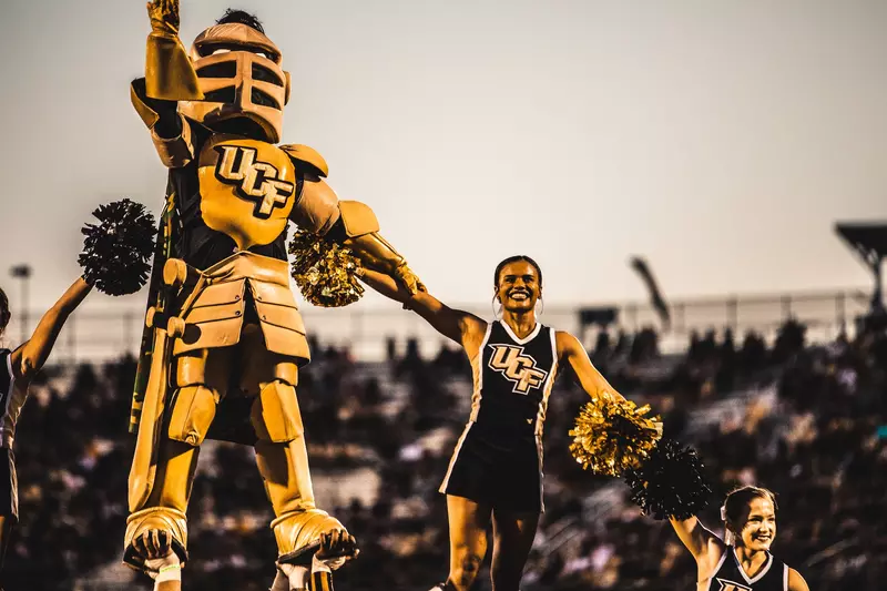 The UCF mascot and cheerleaders during a football game.