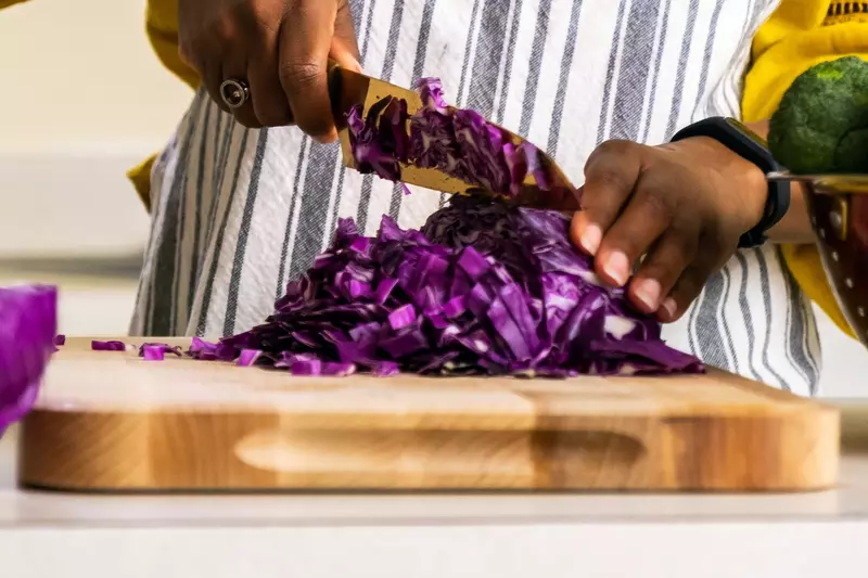 A woman chopping purple cabbage.