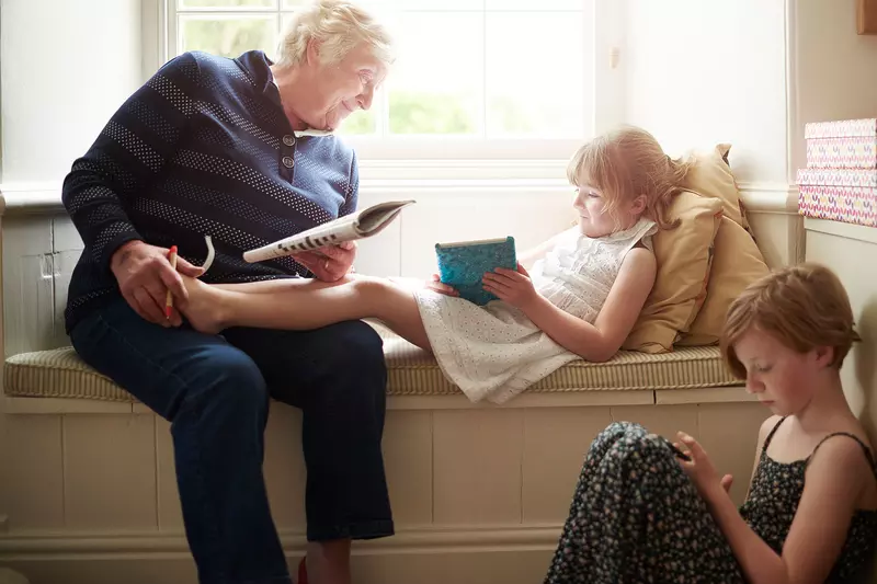 A woman doing a crossword with her grandchildren.