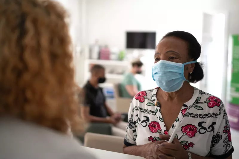 A woman visiting a medical provider wearing a mask.