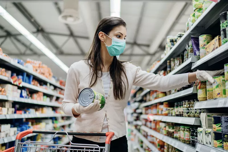 A woman shopping at the grocery store wearing a mask.