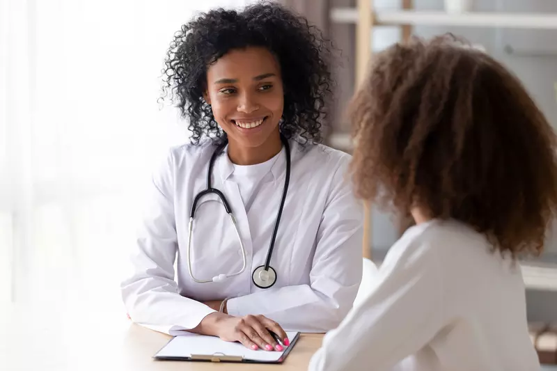A black female doctor talks to an adult woman patient
