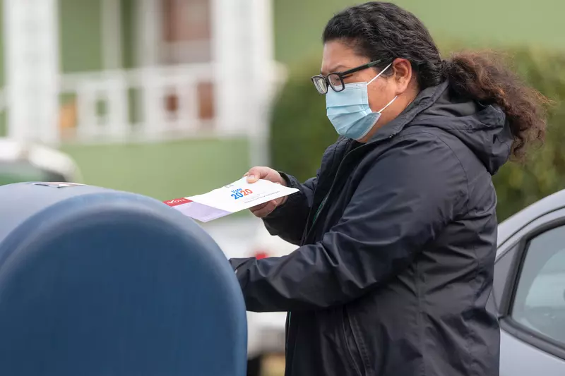 A woman dropping in her 2020 mail-in ballot