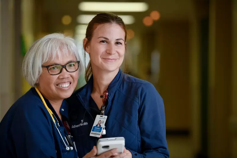 Two nurses from AdventHealth Palm Coast, smiling and looking to the right of the camera