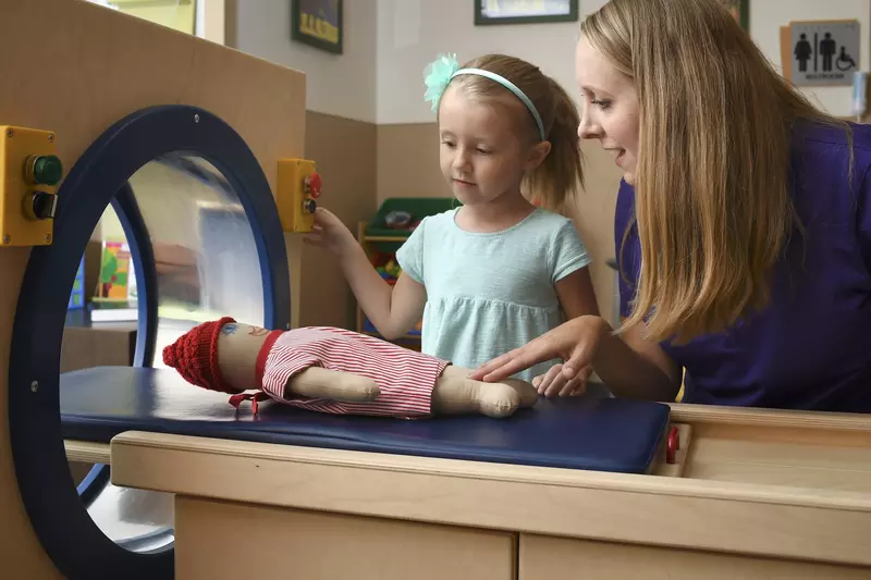 An imaging technician shows a child what to expect during an MRI.