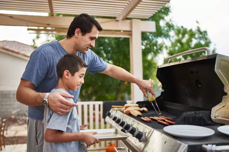 A father and son grilling on the porch.
