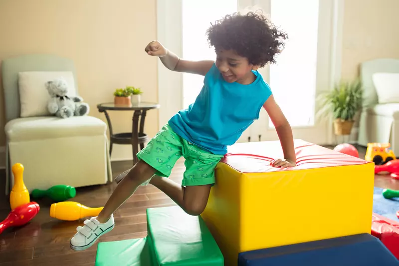A little boy jumping in the family room.