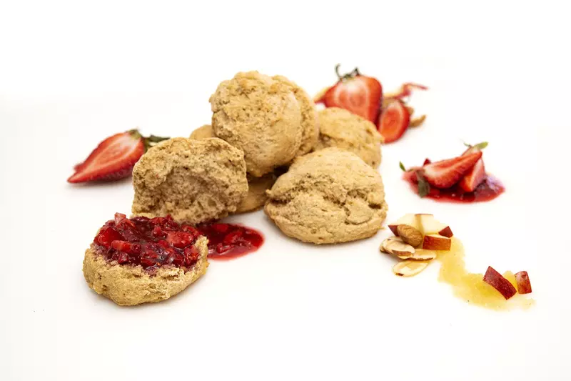a pile of five fresh baked biscuits, topped with strawberry puree and surrounded by strawberry slices