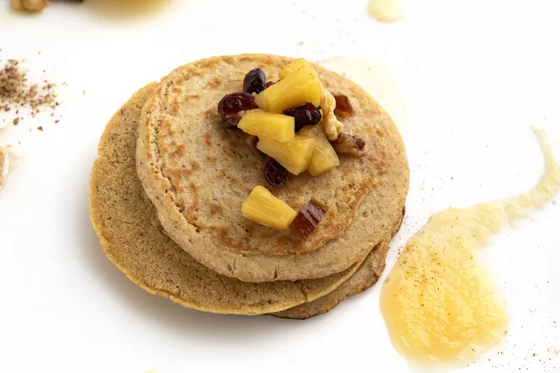 Stack of whole wheat pancakes with fruit and applesauce garnish