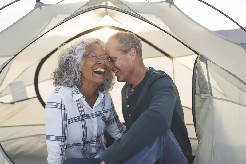 man and woman camping in tent with sun shining