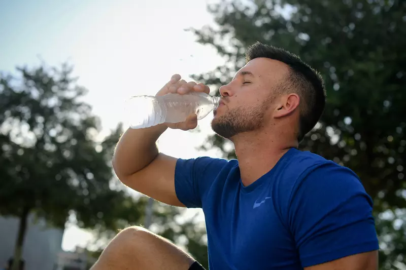 A young man drinking a water-bottle after exercising. 
