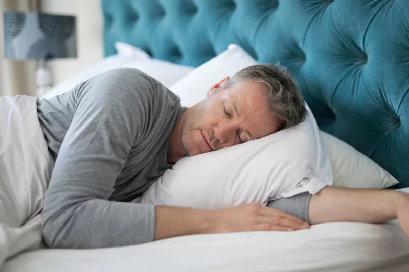 Man taking a nap in bed at home.