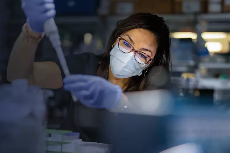 Masked Woman in Lab holding a syringe