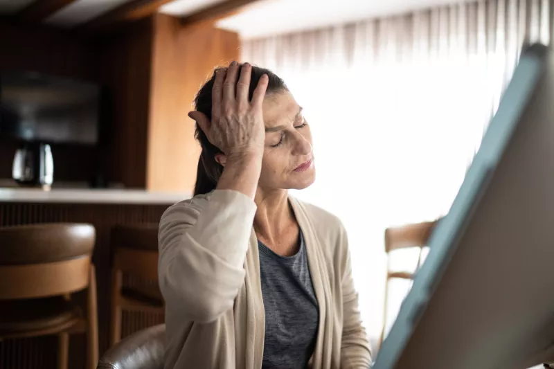 An older woman holding her hand to her head.