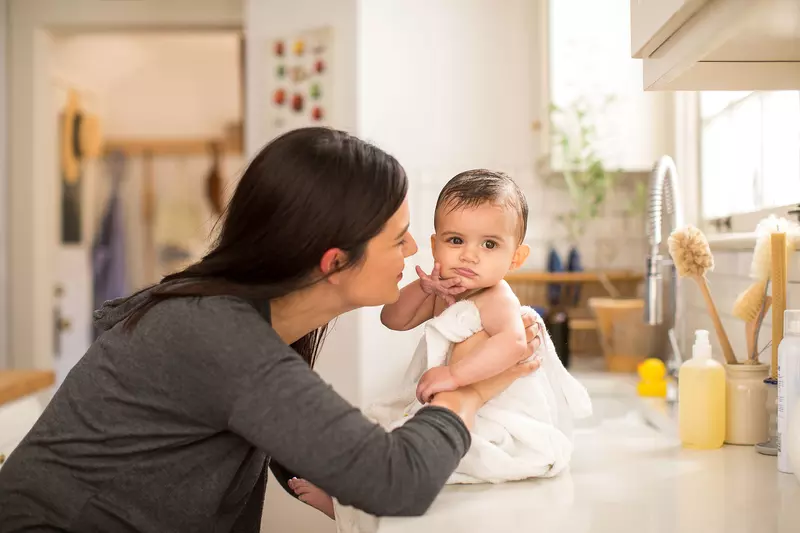 A mom drying her baby in the kitchen's counter-top.