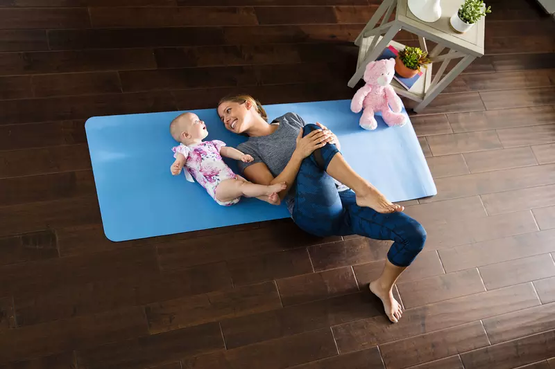 A mom stretching with her baby girl in the living room